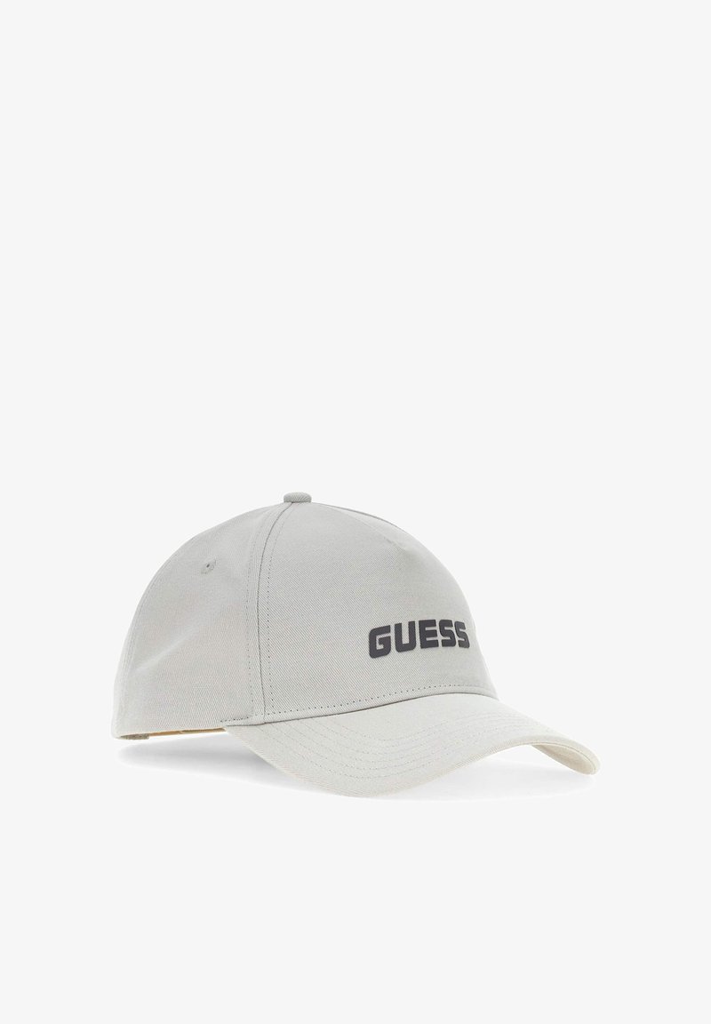 Casquette de baseball gris clair avec visière courbée et logo noir "GUESS" à l'avant, présentée sur un fond blanc.