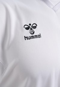 Wit sportshirt met zwart Hummel-logo en gestileerd hommelsymbool op de borst.