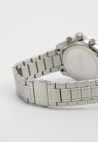 Ρολόι από ανοξείδωτο ατσάλι με γυαλιστερή φινίρισμα, που διαθέτει στέρεο μπρασελέ, χαρακτικό λογότυπο "BOSS", χρονογράφους και μεταλλικά κουμπιά.