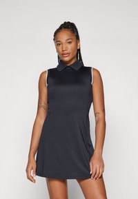 Svart ärmlös polo-klänning med krage, vita detaljer vid ärmhålen och en figurnära passform. Slät, lätt tyg.