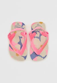 Tongs en caoutchouc rose avec une semelle texturée, présentant un motif floral multicolore avec des accents bleus, roses et dorés. Logo de la marque présent.