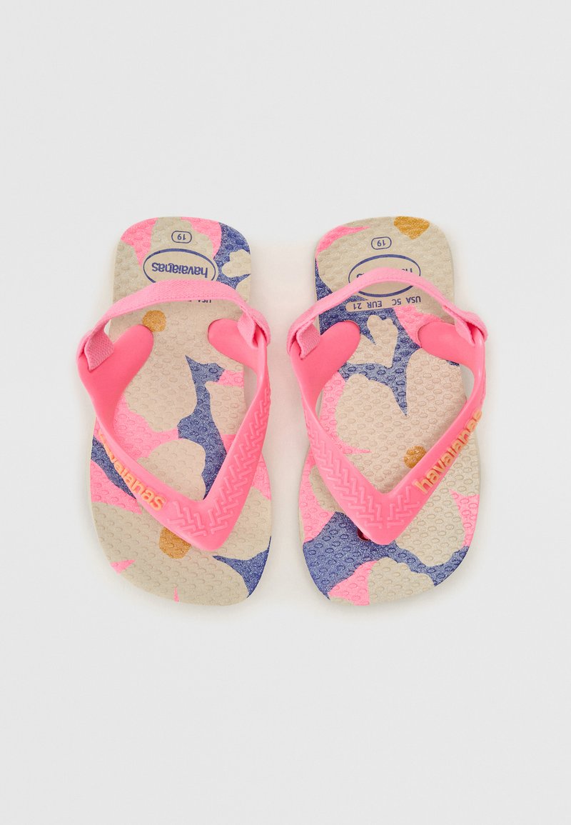 Tongs en caoutchouc rose avec une semelle texturée, présentant un motif floral multicolore avec des accents bleus, roses et dorés. Logo de la marque présent.