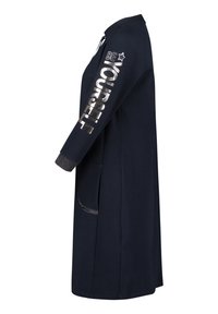 Granatowy długi płaszcz z zapięciem na zamek, tekst "BĄDŹ SOBĄ" w metalicznej srebności na rękawie oraz teksturowane mankiety rękawów i boczne kieszenie.