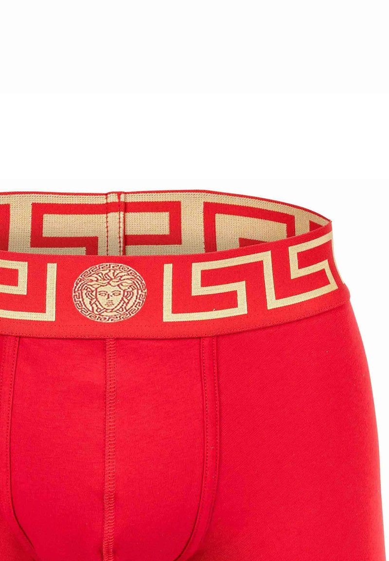 Rote Boxer-Shorts mit einem goldfarbenen, geometrisch gemusterten Bündchen und Logo-Detail. Aus weichem Stoff mit nahtlosem Design hergestellt.