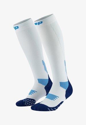 Knee-high compression socks in white and navy, featuring textured patterns, blue accents, and a reinforced toe for support and durability.