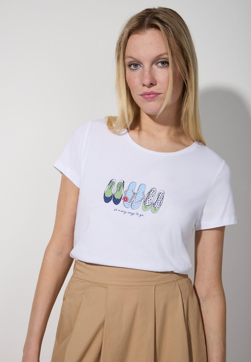 Weißes Baumwoll-T-Shirt mit einem bunten Grafikdesign von Schuhen in unterschiedlichen Mustern und dem Text "so viele Wege zu gehen". Kurze Ärmel, klassische Passform.