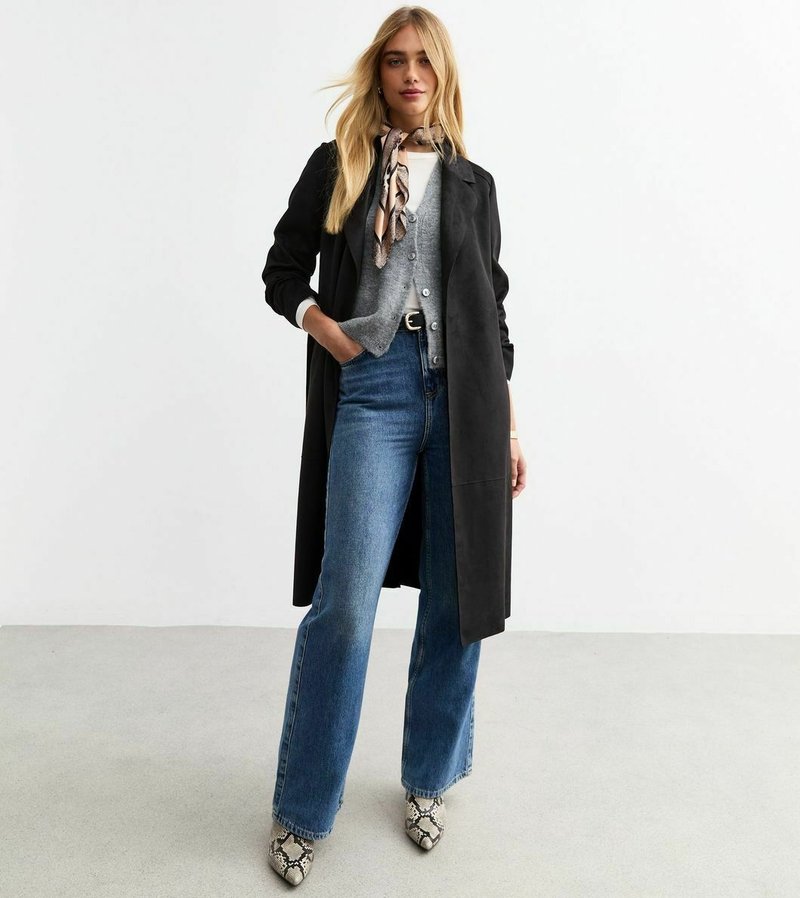 Svart lång kappa över en grå cardigan, ihop med högmidjade blå utsvängda jeans och spetiga klackar med ormskinnsmönster. Silkscarf ger en detalj.