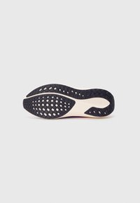 Black rubber outsole with a textured pattern, smooth midsole in cream, featuring a subtle logo detail. Curved shape for ergonomic design.