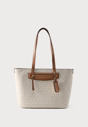 Bézs nagy táska barna bőr fogantyúkkal, elülső cipzáras zsebbel és az egész felületen ismétlődő "MK" logómintával.