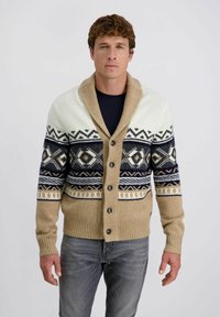 Gebreide cardigan in beige en wit met marineblauwe geometrische patronen en een sjawlboord. Bevat vijf knopen en ribgebreide manchetten en zoom.