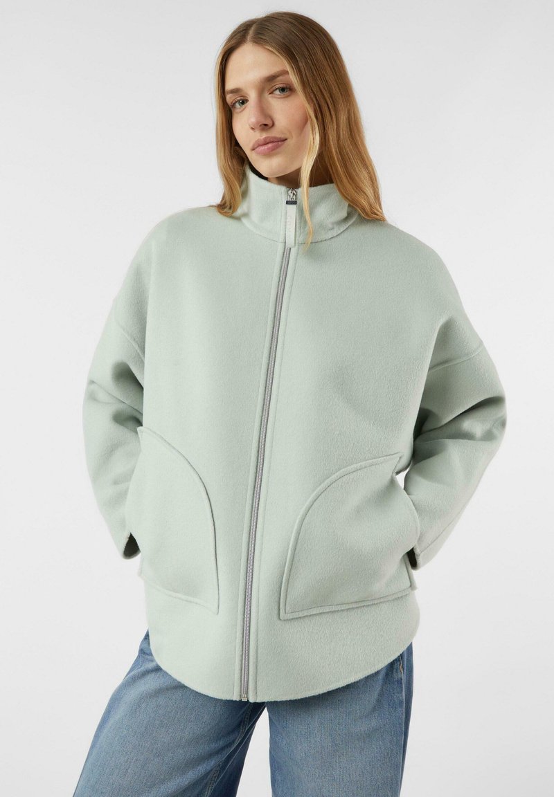 Lichtgroene fleece jas met een hoge kraag, ritssluiting aan de voorkant en grote zijzakken, met een zachte textuur en een comfortabele pasvorm.