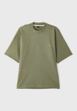 T-shirt en coton vert olive à manches courtes, col rond et détail textuel à l'avant en blanc et orange. Texture lisse, coupe décontractée.