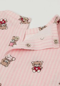 Růžová pruhovaná látka s potiskem medvídků, s kovovými patentkami na límci, hladká textura a hravý design.