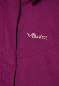 Fioletowa kurtka z tkaniny o gładkiej fakturze i subtelnym połysku. Posiada haftowane logo "TROLLKIDS" w jasnym kolorze.