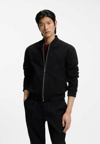 Black suede bomber jacket with a front zip closure, ribbed cuffs, and hem. Smooth texture with a fitted design and side pockets.