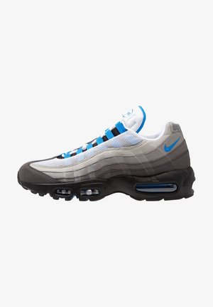 Baskets de sport avec des couches blanches, grises et noires, des accents bleus, un amorti à air visible et un logo Nike bleu au talon.