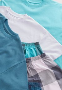 Tre crewneck-T-shirts i grønblå, hvid og lyseblå sammen med tre par elastikbuks i blå stribet og gråt ternet mønster.