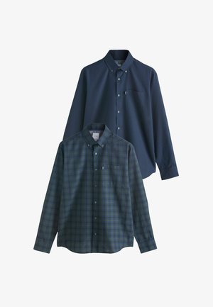 Două cămăși cu mânecă lungă: una de culoare albastru închis solidă cu un buzunar pe piept, cealaltă cu carouri albastre și verzi. Ambele au închidere cu nasturi.