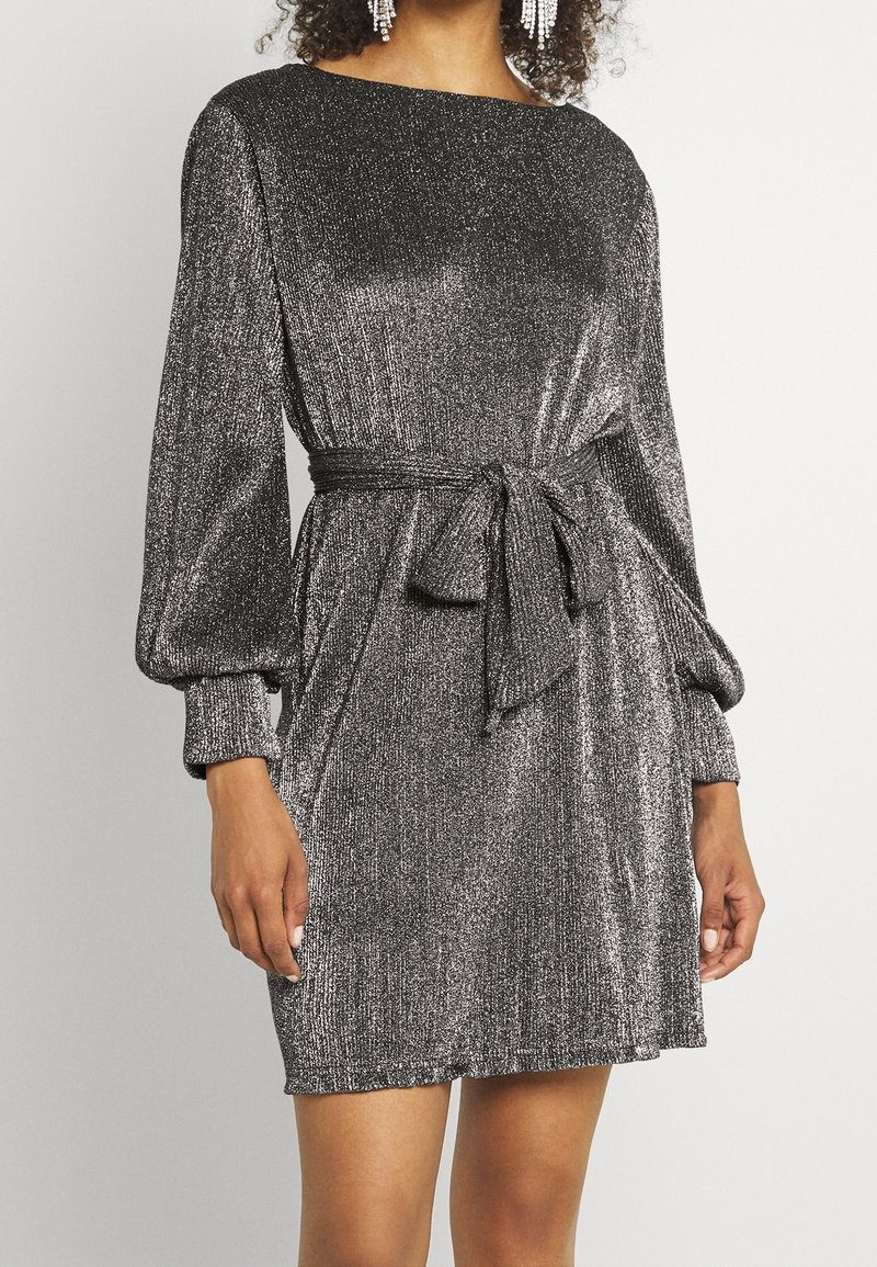 Silver shimmer-klänning med båtformad halsringning, långa puffärmar och en midjebanddetalj. Tyget har en texturerad metallisk yta.