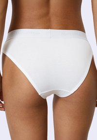 Witte katoenen ondergoed met een brede elastische tailleband en een subtiele logo. Gladde textuur, klassieke slipvorm en aansluitende snit.