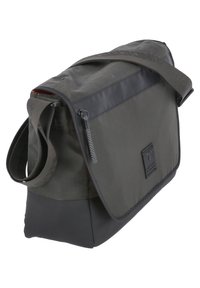 Schoudertas in donkergrijs met een ritszak, verstelbare schouderband en een gladde textuur. Heeft een logopatch en een klepsluiting.