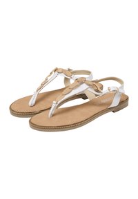 Sandales plates blanches avec des détails tressés dorés, présentant un design à entre-doigt et une semelle texturée couleur tan. Boucle ajustable à la bride de cheville.