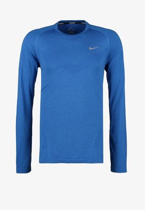 Blue long-sleeve athletic shirt with textured pattern, paired with black shorts and black running shoes, depicting a casual sports look.