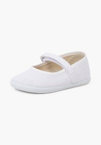 Chaussure bébé de style Mary Jane en tissu blanc avec une seule bride en Velcro et une semelle blanche souple, présentée légèrement de biais vers la gauche sur fond blanc.