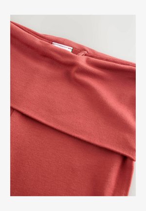 Material elastic și moale într-o nuanță corală discretă, cu un detaliu de talie pliată. Prezintă o textură netedă și o etichetă interioară cu instrucțiuni de întreținere.