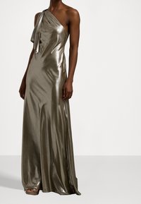 Robe métallisée grise, une épaule, avec un drapé doux et un détail en nœud au niveau du col, présentant une silhouette élégante et fluide ainsi qu'une texture brillante.