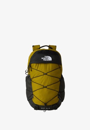 Sac à dos jaune et noir avec un tissu texturé, des bretelles ajustables et un cordon élastique à l'avant pour le rangement. Design durable, logo de la marque visible.