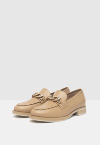 Beige Leder Slipper mit glatter Oberfläche, ausgestattet mit einem goldenen Kettenakzent auf dem Obermaterial und einem niedrigen, gestapelten Absatz.