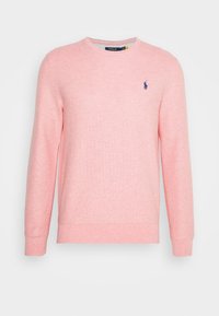 Sweatshirt rose clair avec une finition texturée, col rond et manches longues. Présente un petit logo bleu sur la poitrine.