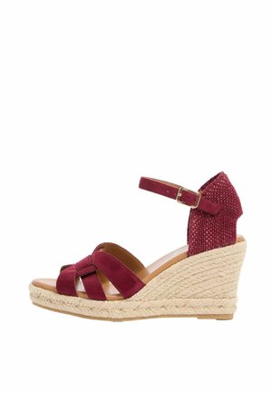 Sandalo con zeppa color bordeaux con tacco intrecciato, cinturino alla caviglia con fibbia e cinturini incrociati in camoscio sopra la punta aperta.