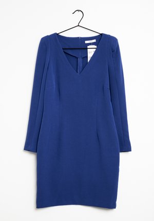 Blauwe jurk met lange mouwen en V-hals en een getailleerde taille, hangend aan een zwarte hanger tegen een witte achtergrond, met een zichtbare rits aan de achterkant en prijskaartje.