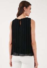 Top plissettato nero con scollatura rotonda e dettaglio a forchetta sul retro. Tessuto leggero con una vestibilità fluida. Adatto per occasioni formali.