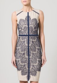 Námořnické šaty s krajkovou vrstvou a krémovým podkladem, zdobené složitými květinovými vzory, s přiléhavým střihem a kulatým výstřihem.