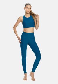Teal színű sport crop top és magas derekú leggings, sima, rugalmas anyagból készült, zökkenőmentes dizájnnal és testhezálló fazonnal.