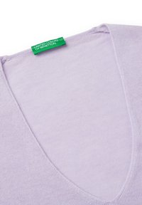 Liliowa sweter w serek z miękkiego dzianiny. Posiada zieloną metkę z napisem "UNITED COLORS OF BENETTON" wewnątrz dekoltu.