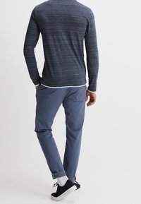 Mörkblå långärmad skjorta med strukturerat, melerat mönster, parat med ljusblå, smal passform byxor. Avslutad med svarta sneakers och vita strumpor.