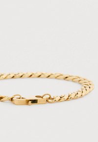 Goldfarbener Kettenarmband mit ineinander verflochtenen Gliedern und einem Verschluss, der den eingravierten Markennamen trägt. Glatte metallische Textur.