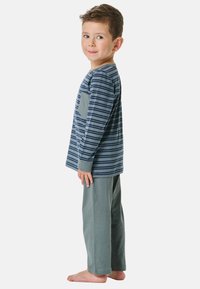 Gestreiftes Langarmhemd in Marineblau und Grau mit einer grauen Tasche, kombiniert mit einfarbigen grauen Hosen. Weicher Baumwollstoff, lässige Passform, keine sichtbaren Hardware-Teile.