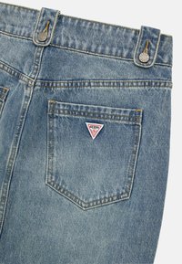 Lichtblauwe denim jeans met twee achterzakken. Driehoekige logopatch op de rechterzak. Kenmerkende stiksels en knoopaccenten.