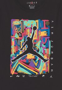 Svart T-shirt med en färgglad grafik av en hoppande figur, lager av geometriska former och detaljerad text. Tillverkad av bomullstyg.