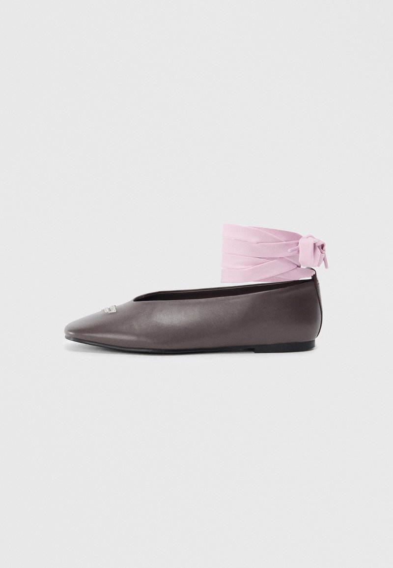 Brown pointed flat shoe with decorative silver detail and pink ankle-wrap ribbon on white background.