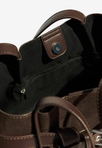 Prune nahk- ja suede-kott, mille sees on must kangasvooder, magnetklõpsuga sulgemine ja tõmblukuga tasku.