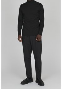 Svart polokrage långärmad topp som matchas med svarta slim-fit byxor och svarta slip-on skor. Slät tyg med minimala sömmar.