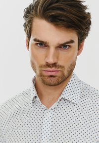 Biała koszula z guzikiem, z niebieskim wzorem w romby i usztywnionym kołnierzykiem. Gładka faktura tkaniny, z lekkim połyskiem.