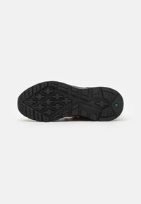 Talpă din cauciuc negru cu un model texturat pentru aderență, având un accent verde și logo-ul Timberland. Design durabil pentru tracțiune și stabilitate.