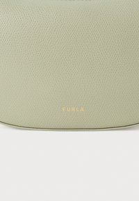 Bolsa de mão de couro verde texturizado com um logo "FURLA" em relevo dourado. Possui uma forma arredondada e bordas suaves.